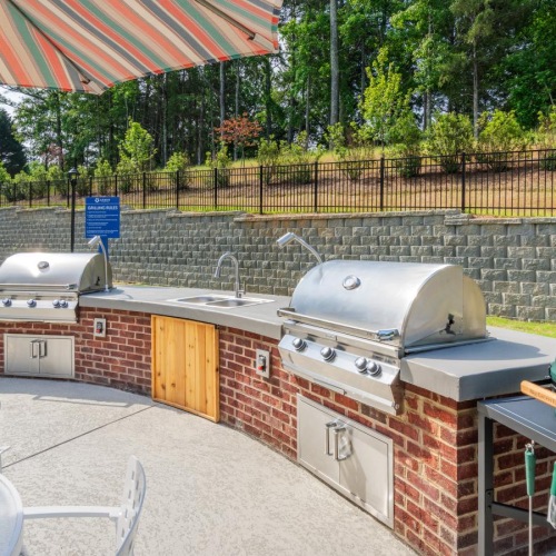 Take advantage of all Arden at Indian Land has to offer The outdoor lounge at Arden at Indian Land Apartments in South Carolina, featuring grill stations and a table with chairs.